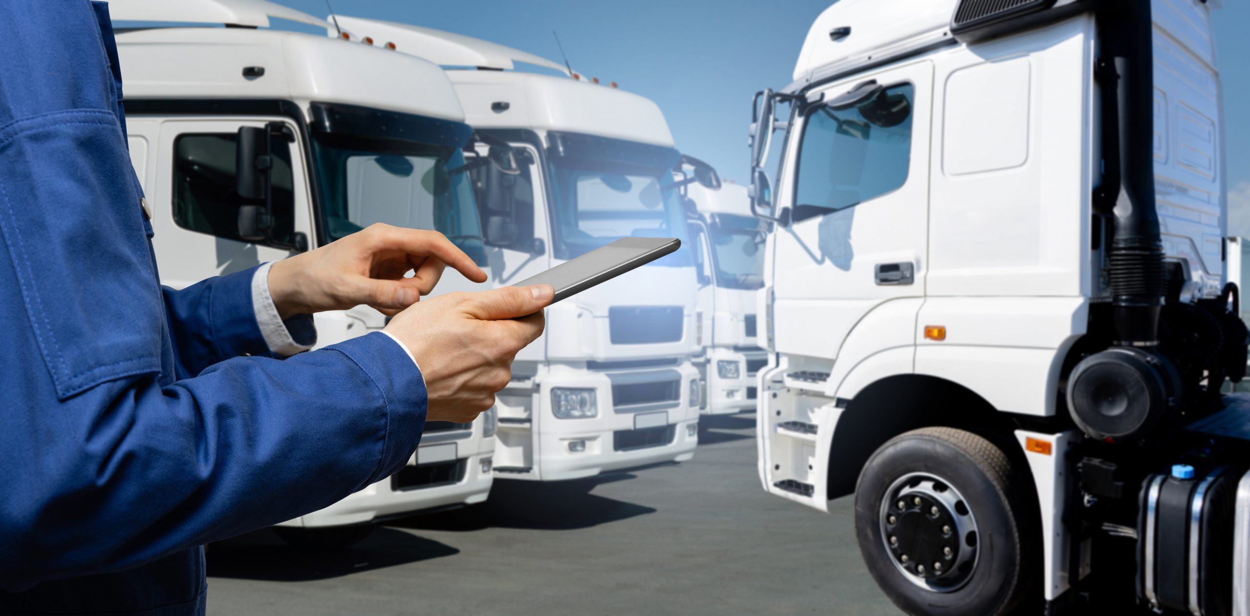 Common Misconceptions About Goods in Transit Insurance a man in blue uniform oversees multiple white trucks with transit insurance